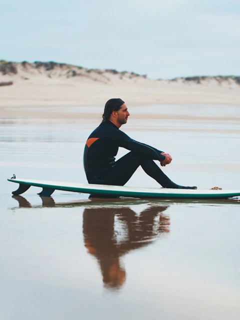 Surfer sitting on surfboard by the shore
